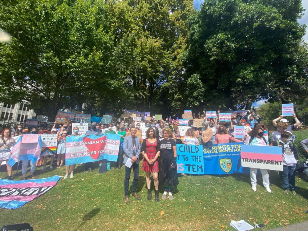 A large crowd of people with placards and messages of support for the transgender community, gathered in a park near Hobart Town Hall.